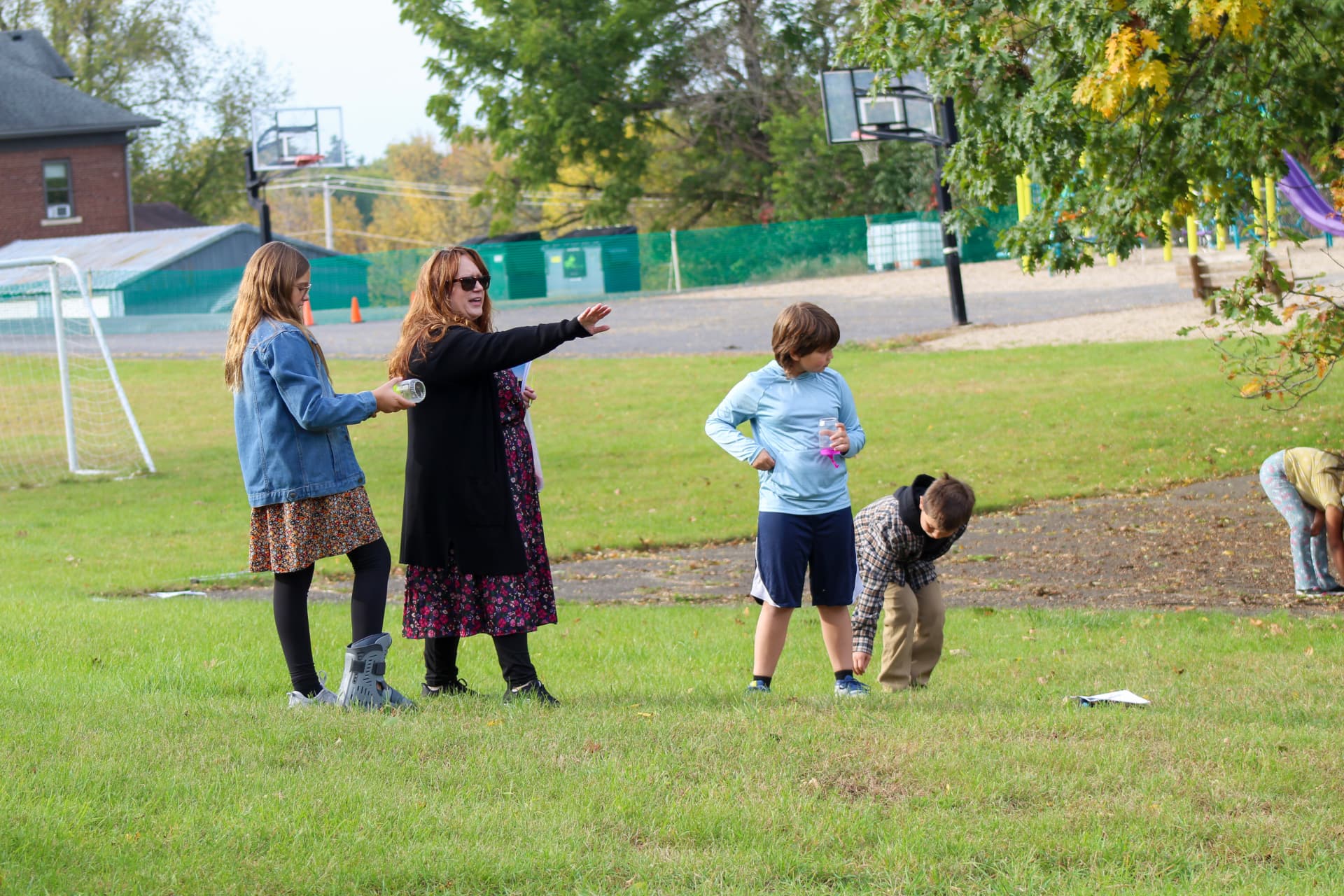 A teacher guides students during an outdoor activity on the school lawn