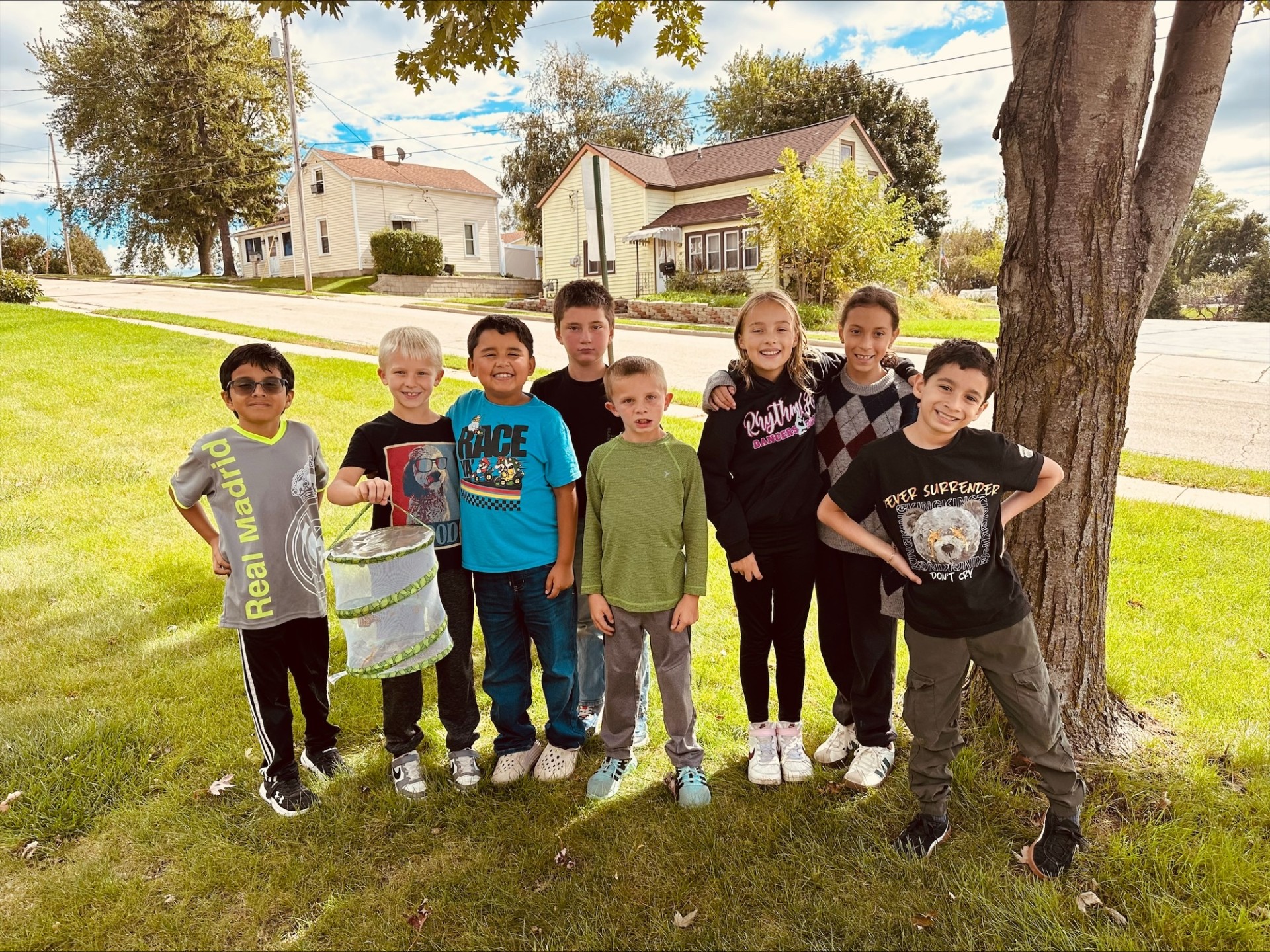 St. Mary students posing together outdoors on a sunny day, one holding a butterfly release cage